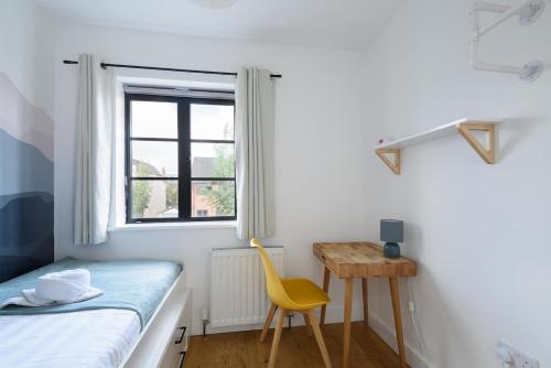 a bedroom with a bed and a desk and a yellow chair at Spacious 4 Bedroom House by Oxford Train Station in Oxford