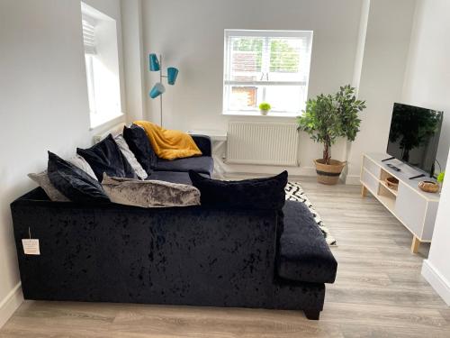 a living room with a black couch and a tv at Exclusive 1 and 2 Bedroom Flats only 0,5 miles aw in Bicester