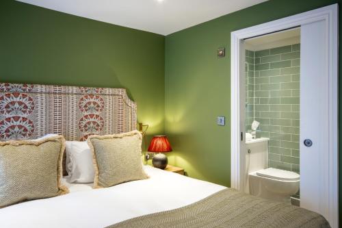 a green bedroom with a bed and a toilet at The Bell Hotel, Saxmundham in Saxmundham