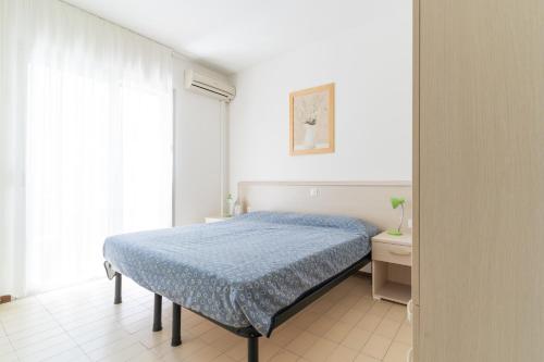 a white bedroom with a bed and a window at Residence Selenis Apartments in Caorle