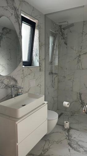 a white bathroom with a sink and a toilet at Šumska Duša in Banja Luka