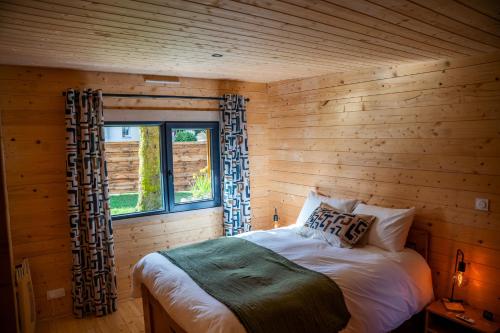 a bed in a wooden room with a window at Gîte de charme Ò Chalet in Camors