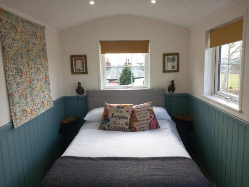a small bedroom with a bed with two pillows at The Mad Hatter's Shepherd's Hut in Carlisle