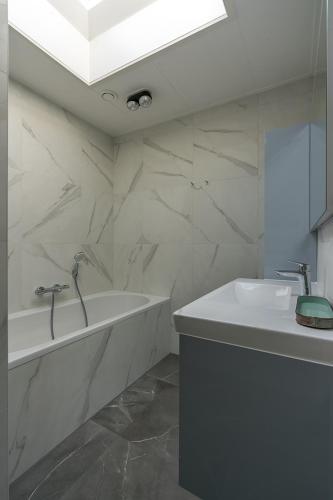 a white bathroom with a sink and a tub at Zilte Bries in De Koog