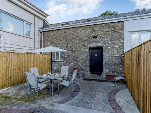 a patio with a table with chairs and an umbrella at The Cottage-Uk32854 in Neath