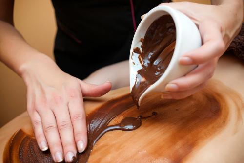 a woman is pouring chocolate onto a wooden cutting board at Hotel Klaudia in Juszczyn