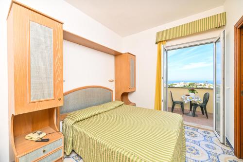 a bedroom with a bed and a balcony with a table at Hotel Tramonto d'oro Terme Casthotels in Forio d'Ischia