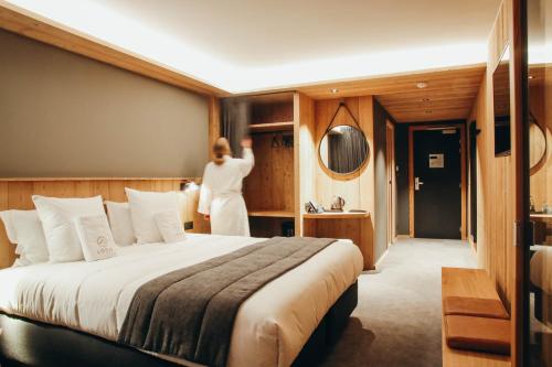 a woman standing in a hotel room with a bed at Lodji Hotel & spa in Saint-Martin-de-Belleville
