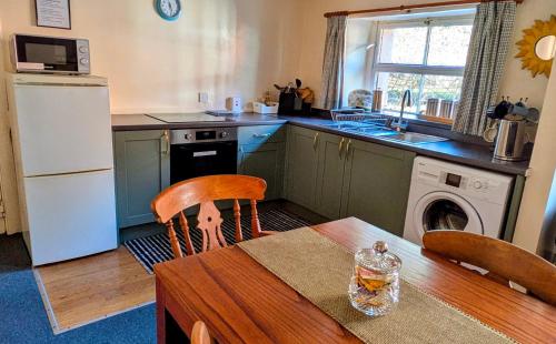 a kitchen with a wooden table and a kitchen with a refrigerator at Strathpeffer Holiday Cottages in Strathpeffer