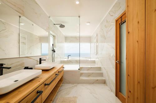 a bathroom with two sinks and a tub and a shower at Casa do Mar - North Coast Ocean Views in Calhetas