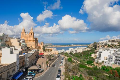 a city street with buildings and the ocean in the background at Maritim Antonine Hotel & Spa in Mellieħa