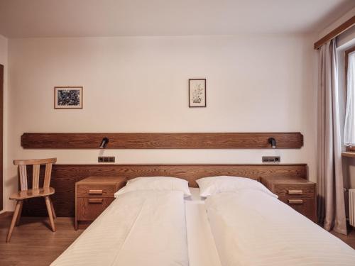 a bedroom with two beds and a chair at Fermeda in Villnoss