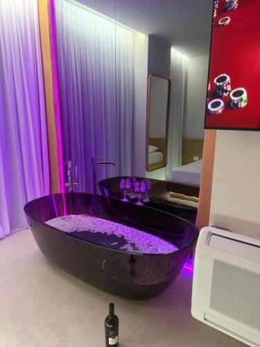 a black tub in a bathroom with purple lighting at Solea Apartment in Vlorë