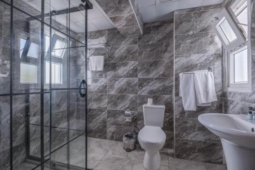 a bathroom with a shower and a toilet and a sink at The Gap Hotel Kuşadası in Kuşadası