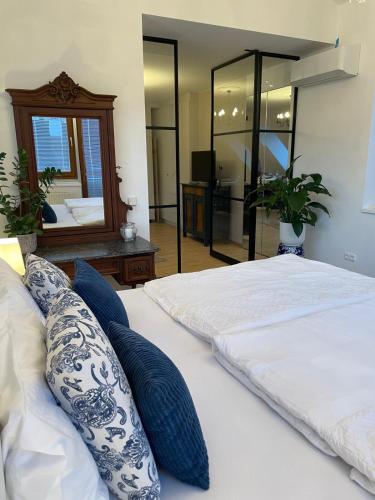a bedroom with a white bed with blue pillows and a mirror at Amadeus Studio in Baden