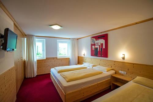 a bedroom with two beds and a flat screen tv at Alpenhaus Montafon by Pferd auf Wolke in Gargellen