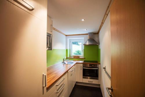 a kitchen with white cabinets and green walls at Alpenhaus Montafon by Pferd auf Wolke in Gargellen