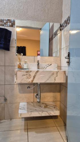 a bathroom with a marble sink and a mirror at Suítes privativas, camas confortáveis, piscina, churrasqueira e playground, Roupa de Cama e tolha de banho. in Rubinéia