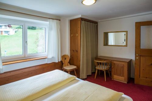 a bedroom with a bed and a desk and a window at Alpenhaus Montafon by Pferd auf Wolke in Gargellen
