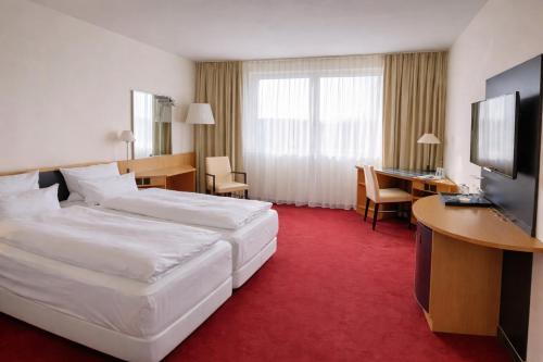 ein Hotelzimmer mit einem großen Bett und einem Schreibtisch in der Unterkunft Hotel Dresden Neustadt in Dresden