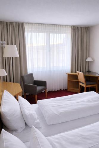 ein Hotelzimmer mit Bett, Stuhl und Schreibtisch in der Unterkunft Hotel Dresden Neustadt in Dresden
