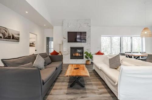a living room with two couches and a fireplace at Chalet Boréale with Private Spa & Billiards, Golf & Carling Lake in Brownsburg