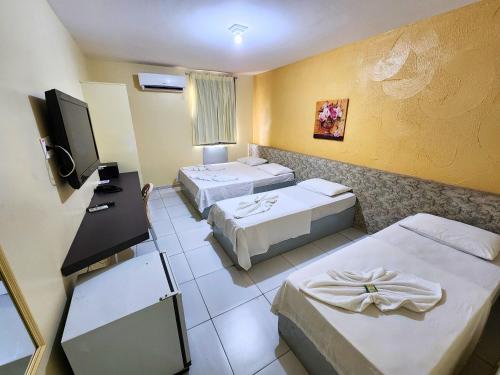 ein Hotelzimmer mit zwei Betten und einem Flachbildfernseher in der Unterkunft JR Hotel in João Pessoa