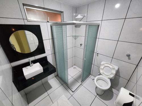 ein Badezimmer mit Toilette, Waschbecken und Spiegel in der Unterkunft JR Hotel in João Pessoa