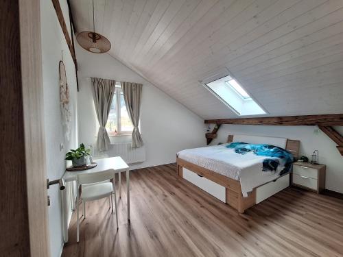 a bedroom with a bed and a desk and windows at Chambres d'hôtes Les Fontaines in Tramelan