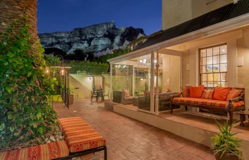a house with a patio with a couch and a table at Rosedene Guest House in Cape Town