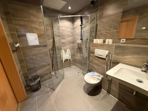 a bathroom with a shower and a toilet and a sink at Boutique Hotel Sena in Berlin