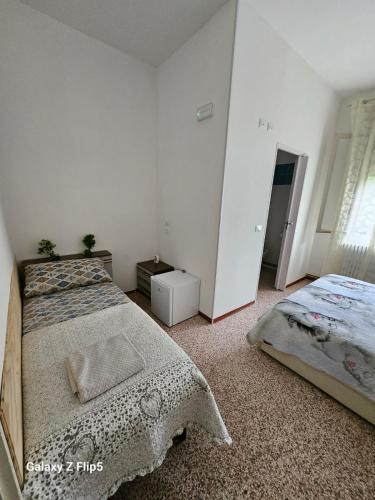 a white bedroom with two beds and a window at B&B Tre di Cuori in Campiano