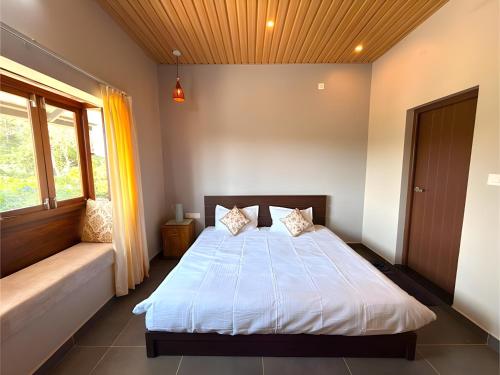 a bedroom with a bed and a window at Evara Stays Coorg in Kushālnagar