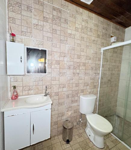 a bathroom with a toilet and a sink and a shower at Ilhabela quarto próx praia in Ilhabela