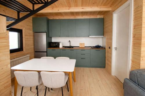 a kitchen with green cabinets and a white table and chairs at Gudauri Deka Alpine Cottages in Gudauri