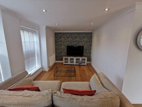 a living room with two couches and a flat screen tv at Flat 12- The Meadow in Banbury