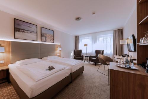 a hotel room with a large bed and a desk at Upstalsboom Parkhotel in Emden