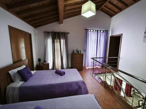 a bedroom with two beds with purple sheets at Arco-Iris in Santo António