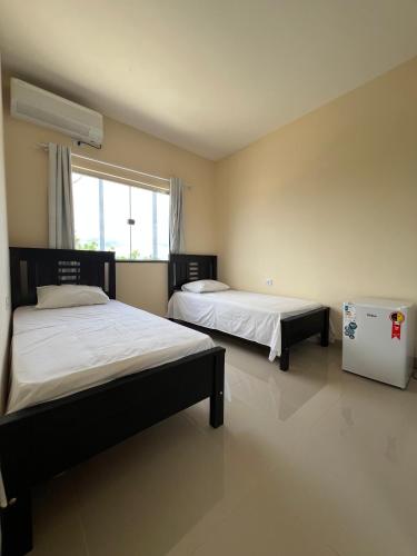 a bedroom with two beds and a window at Hotel Brilhante 2 in Itacarambi