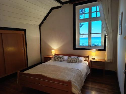 a bedroom with a bed with two lamps and a window at Hostal Los Riscos in Llanquihue