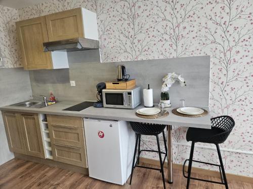 a kitchen with a counter with a microwave and two chairs at Studio Le Belvédère TURCKHEIM in Turckheim