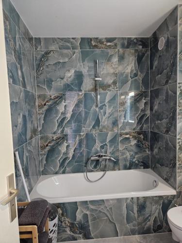 a bath tub in a bathroom with marble tiles at Studio Le Belvédère TURCKHEIM in Turckheim