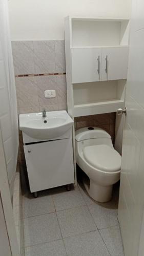 a white bathroom with a toilet and a sink at Casa Excalibur in Máncora