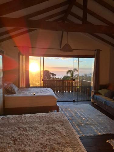 a bedroom with a bed and a balcony with the sunset at Morada Sunset Vista Para o Mar in Praia do Rosa