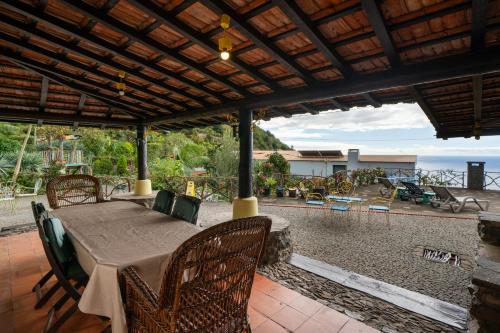 a table and chairs on a patio with a view of the ocean at Antiga Fábrica da Manteiga by An Island Apart in Arco da Calheta