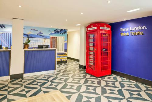 a red phone booth in a room with a blue wall at Thistle London Heathrow Terminal 5 in Hillingdon
