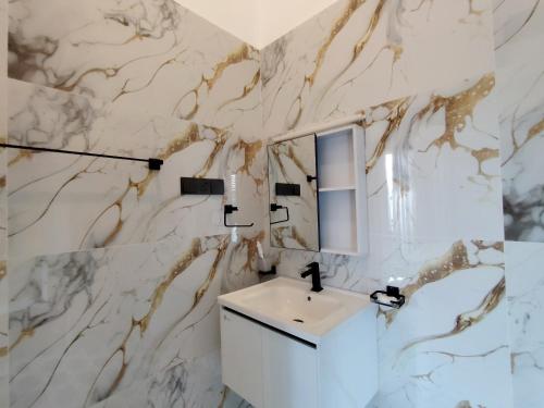 a bathroom with a white sink and a marble wall at Calvian Villa in Walliwala East
