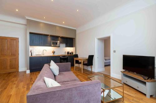 a living room with a couch and a tv and a kitchen at Flat 3- The Warwick in Banbury