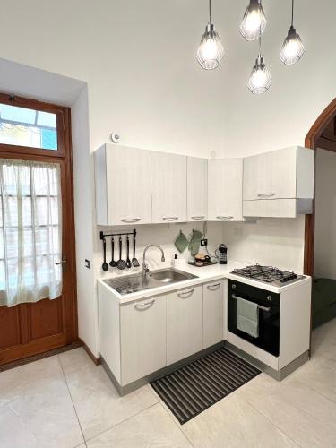 a kitchen with white cabinets and a sink and a stove at Porto Vecchio Apartment in Sanremo