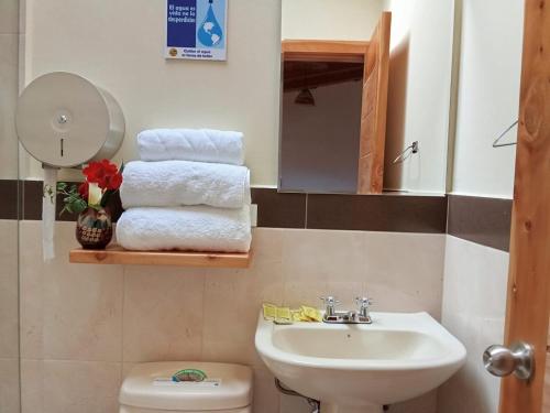 a bathroom with a sink and a toilet and towels at Brisas Del Lago San Pablo in Otavalo